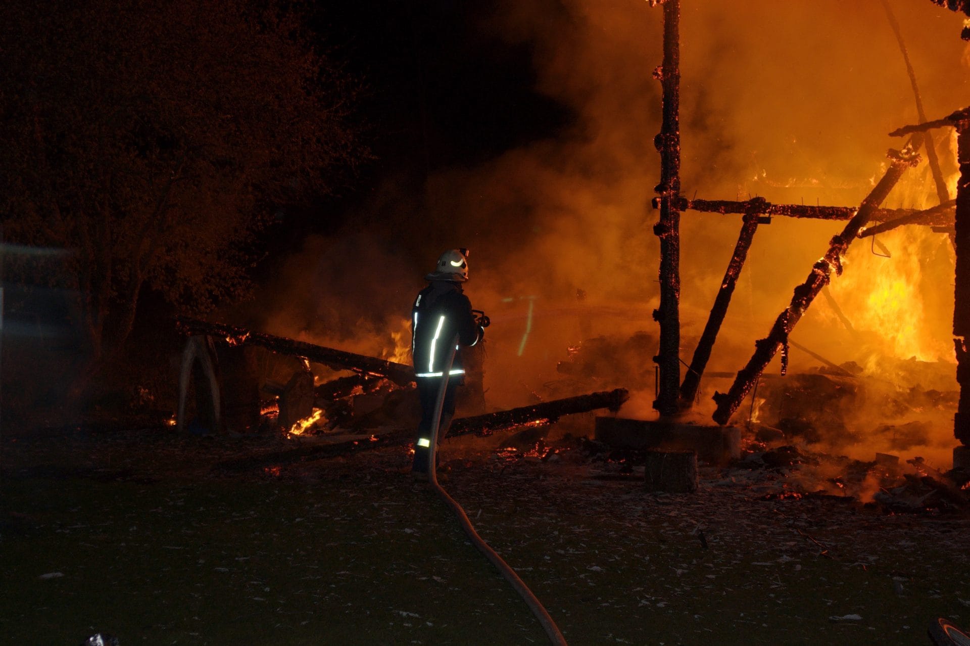 NIKON CORPORATION NIKON D5000 · 55 mm · f/5.6 · 1/60 s A firefighter is standing in front of a burning structure at night.