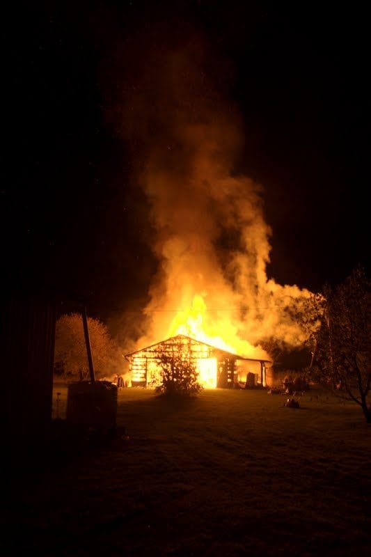 NIKON CORPORATION NIKON D5000 · 18 mm · f/4 · 1/60 s A house engulfed in flames at night, with thick smoke rising into the sky.
