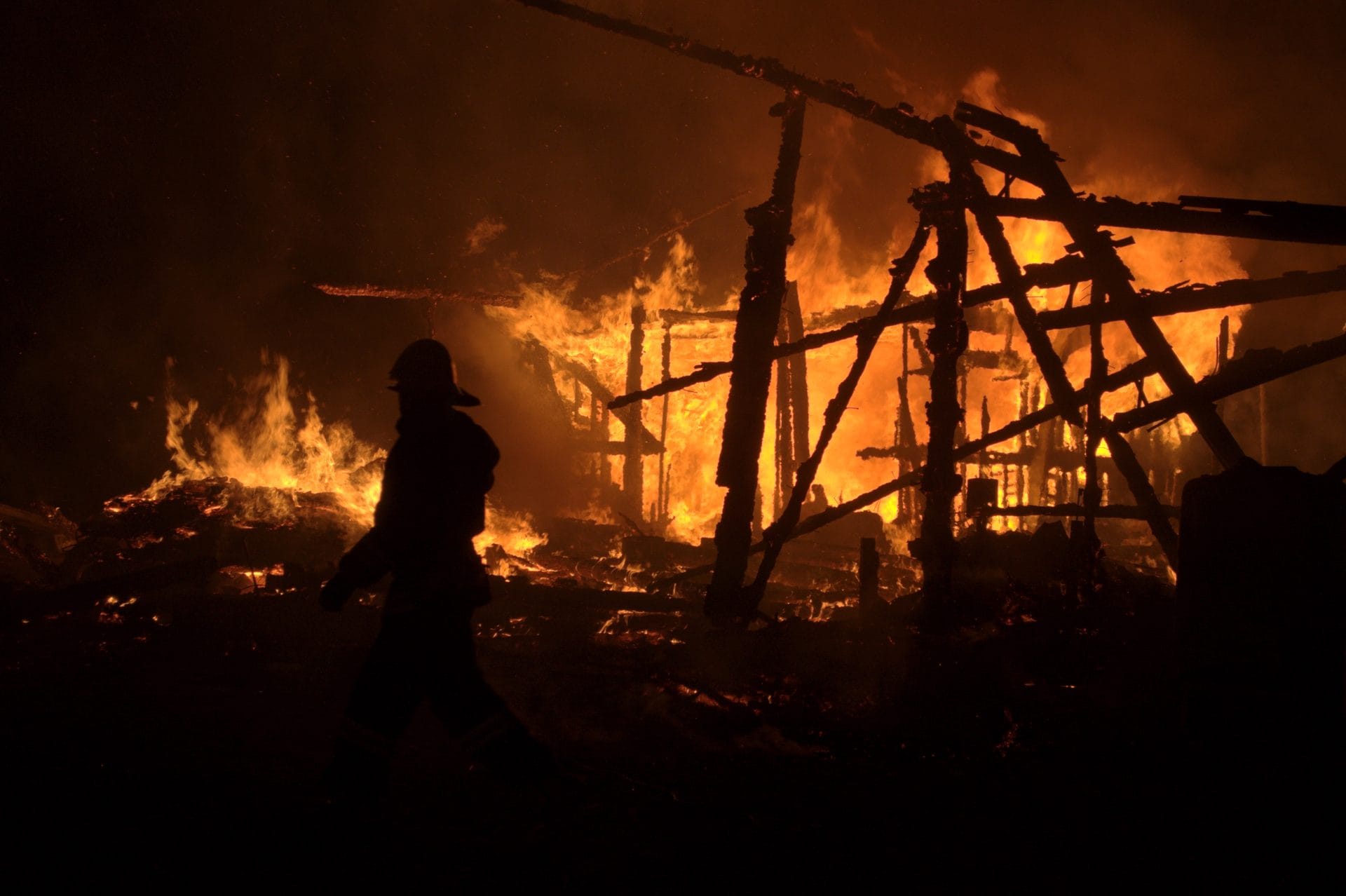 NIKON CORPORATION NIKON D5000 · 44 mm · f/5.6 · 1/125 s A firefighter is silhouetted against a large fire burning in the background, with the flames engulfing what appears to be a wooden structure.