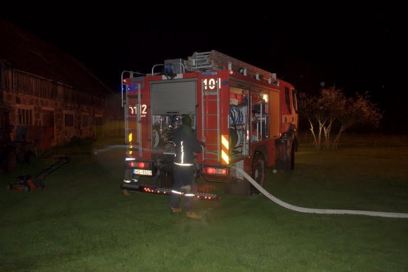 NIKON CORPORATION NIKON D5000 · 18 mm · f/3.5 · 1/60 s A fire truck is parked on a grassy field at night, with a firefighter spraying water from a hose.