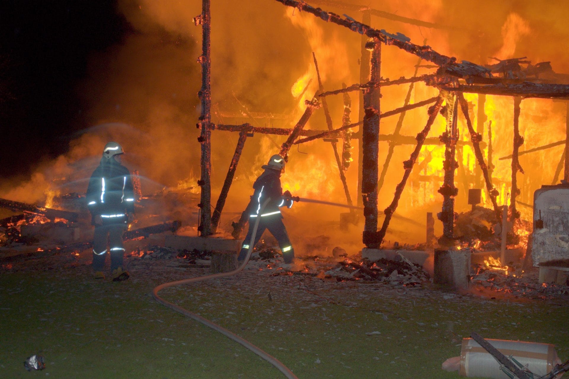 NIKON CORPORATION NIKON D5000 · 48 mm · f/5.3 · 1/60 s Two firefighters are battling a large fire at night.