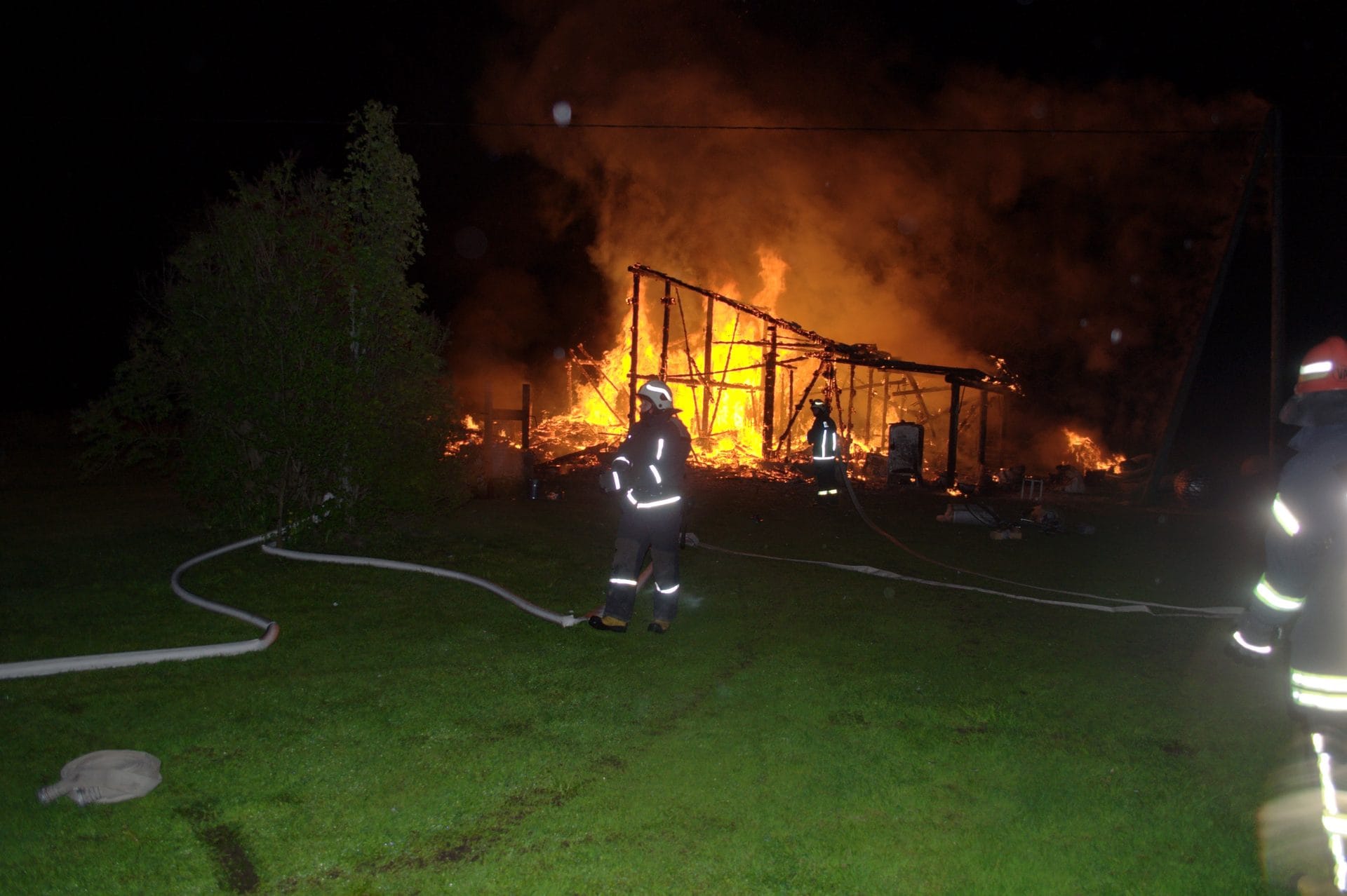 NIKON CORPORATION NIKON D5000 · 18 mm · f/3.5 · 1/200 s A nighttime scene of a large fire burning a wooden structure, with emergency responders present.